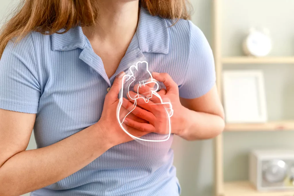 Donna con dolore al petto e illustrazione del cuore, per spiegare che l’uomo non nasce carnivoro e non tollera i grassi animali