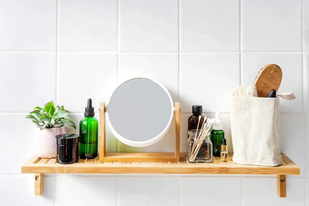 mensola da bagno minimal con specchio, flaconi in vetro, piantina e accessori sostenibili.