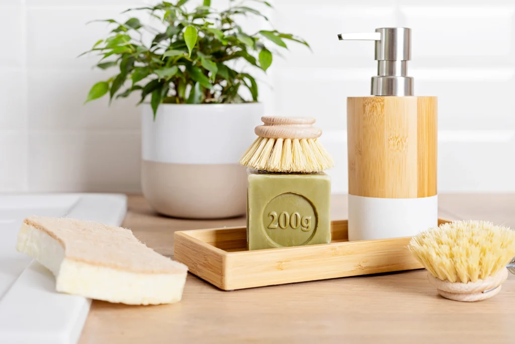 Kit per le pulizie zero waste con sapone solido, spazzole in legno e dispenser riutilizzabile.