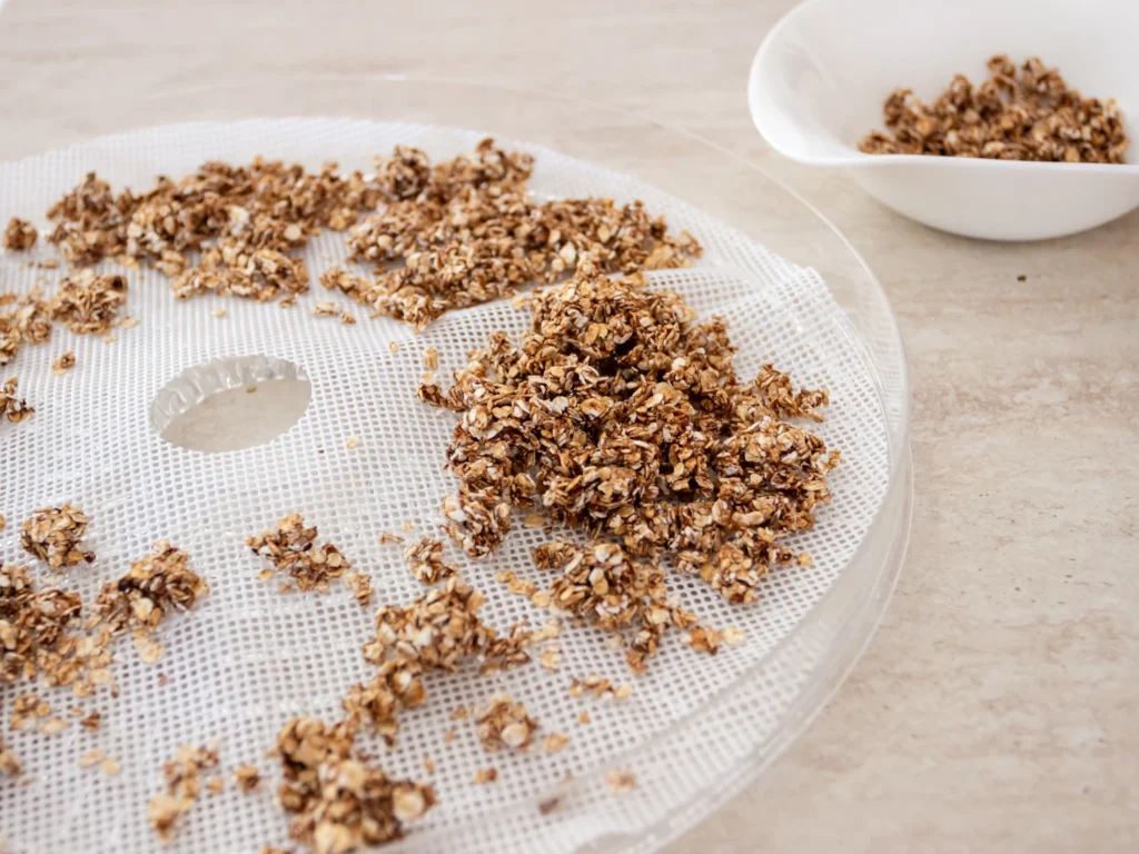 Granola fatta in casa distribuita sul vassoio dell’essiccatore pronta per l’essiccazione