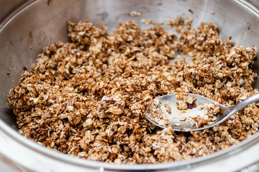 Impasto della granola fatta in casa mescolato in una ciotola d’acciaio con un cucchiaio