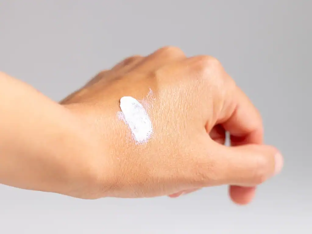 Texture crema solare Sole Bimbi Helan SPF50+ applicata sulla mano, evidenza della consistenza pastosa e del filtro fisico protettivo per bambini.