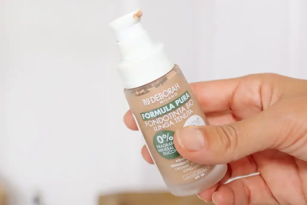 Flacone del fondotinta bio lunga tenuta Deborah Formula Pura tenuto in mano, con dosatore pratico in evidenza.