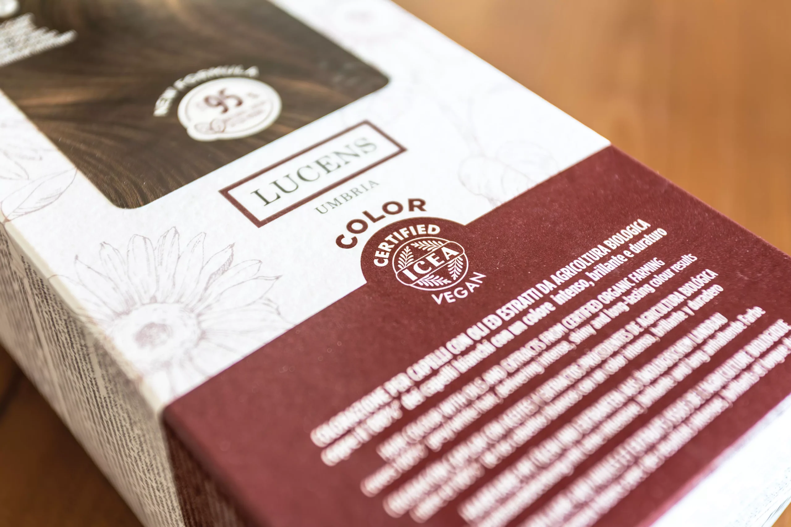 Confezione di tinta vegana Lucens Umbra con certificazione ICEA Vegan su fondo in legno.