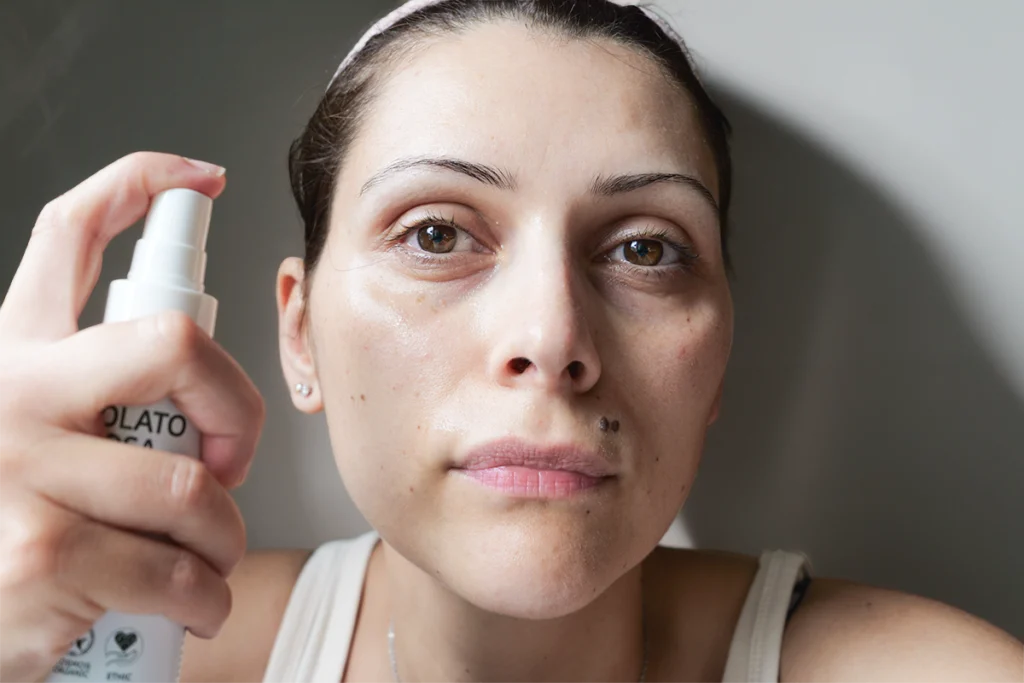 Applicazione dell'Idrolato di Rosa La Saponaria sul viso, donna che spruzza l'idrolato direttamente sulla pelle